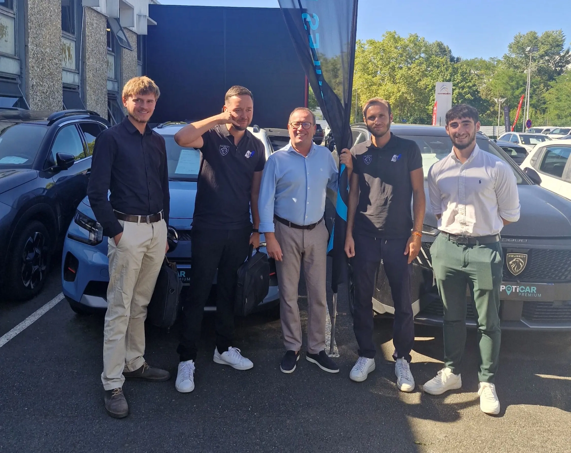Equipe de commerciaux entourant Olivier Ducroix devant un parc automobile